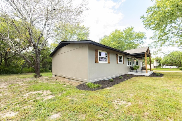 view of side of home with a lawn and a patio area