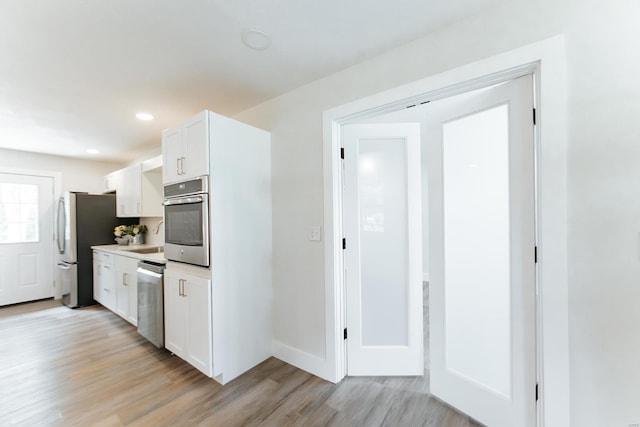 kitchen with light hardwood / wood-style flooring, stainless steel appliances, and white cabinetry