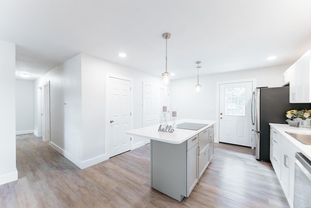 kitchen with pendant lighting, light hardwood / wood-style floors, a center island, white cabinetry, and stainless steel appliances