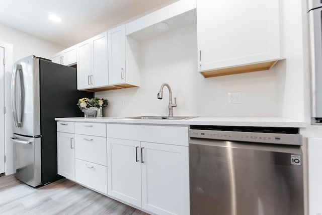 kitchen featuring light hardwood / wood-style flooring, appliances with stainless steel finishes, sink, and white cabinetry