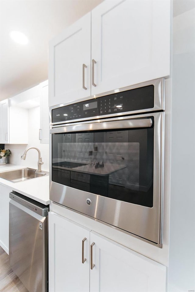 kitchen with light hardwood / wood-style flooring, white cabinets, appliances with stainless steel finishes, and sink