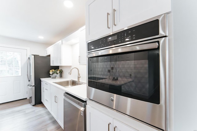 kitchen featuring white cabinets, light hardwood / wood-style floors, appliances with stainless steel finishes, and sink