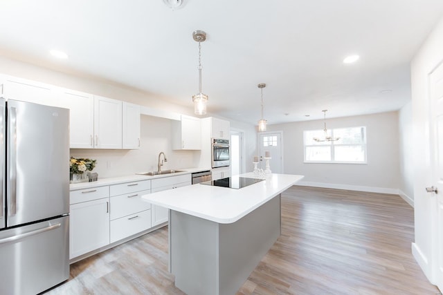 kitchen with light hardwood / wood-style floors, appliances with stainless steel finishes, sink, and white cabinetry