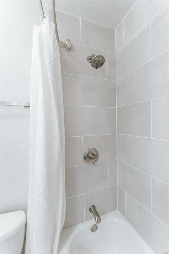 bathroom featuring shower / bath combo, a textured ceiling, and toilet