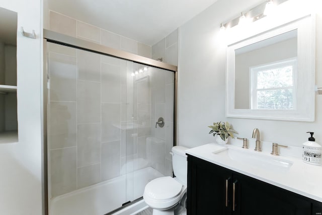 bathroom featuring vanity, toilet, and a shower with door