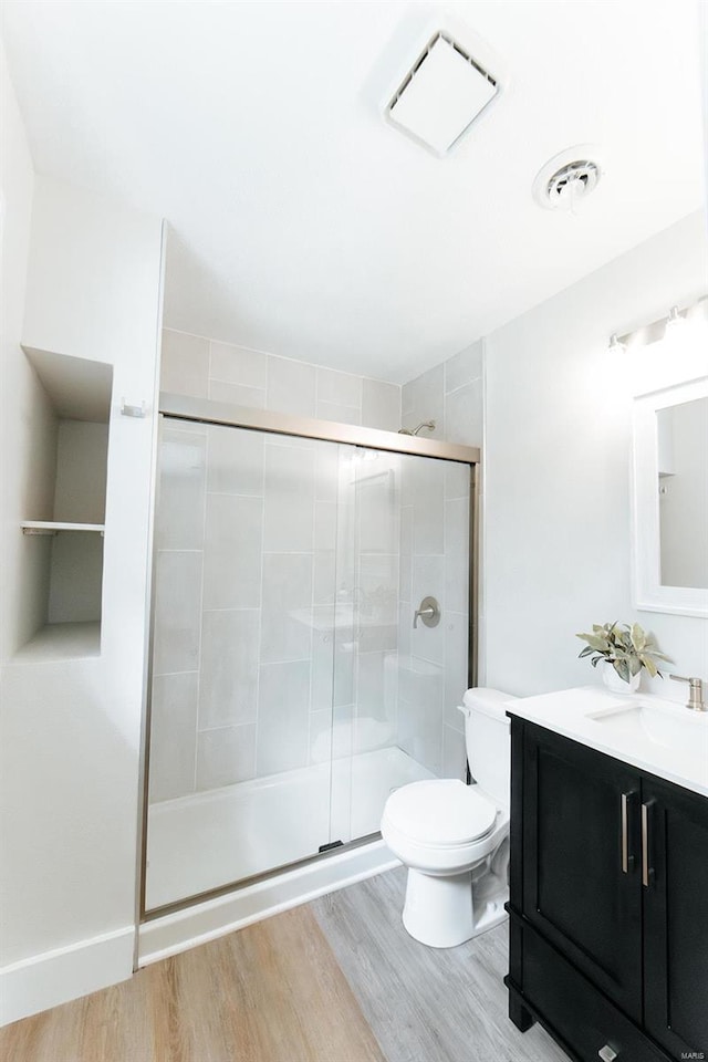 bathroom with vanity, hardwood / wood-style floors, toilet, and an enclosed shower