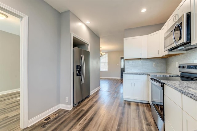 kitchen with dark wood-type flooring, light stone counters, stainless steel appliances, and white cabinets