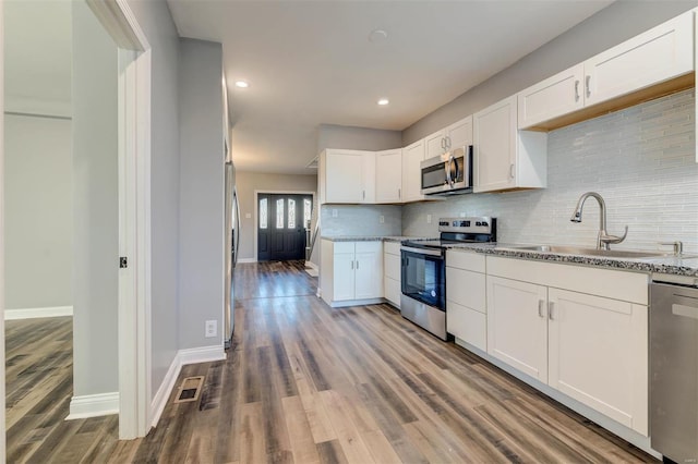 kitchen featuring light stone countertops, appliances with stainless steel finishes, hardwood / wood-style flooring, and white cabinetry