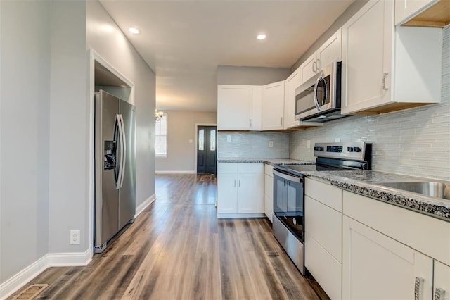 kitchen featuring backsplash, appliances with stainless steel finishes, dark hardwood / wood-style flooring, white cabinetry, and light stone counters