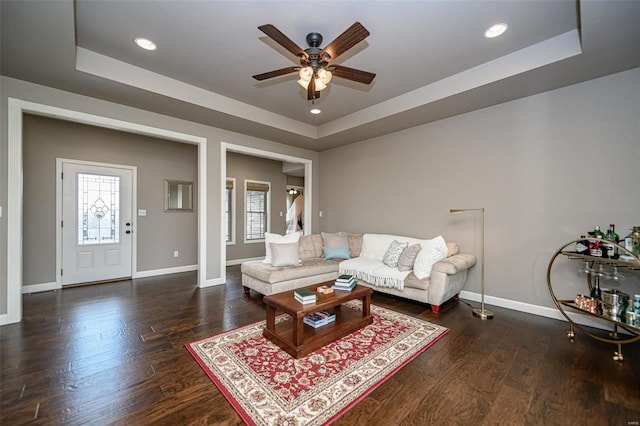 living room with a raised ceiling, hardwood / wood-style flooring, and a healthy amount of sunlight