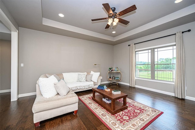 living room with ceiling fan, dark hardwood / wood-style floors, and a tray ceiling