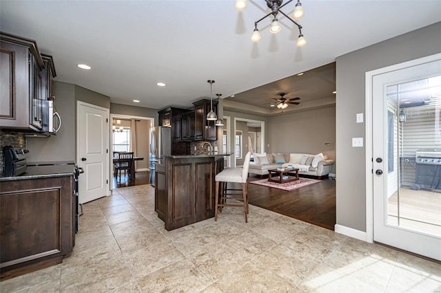 kitchen featuring tasteful backsplash, hanging light fixtures, light hardwood / wood-style flooring, and a kitchen bar