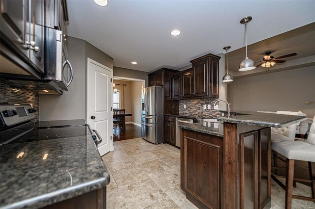 kitchen featuring appliances with stainless steel finishes, light hardwood / wood-style flooring, tasteful backsplash, kitchen peninsula, and pendant lighting