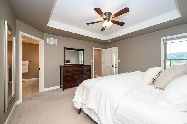 carpeted bedroom featuring ceiling fan and a tray ceiling