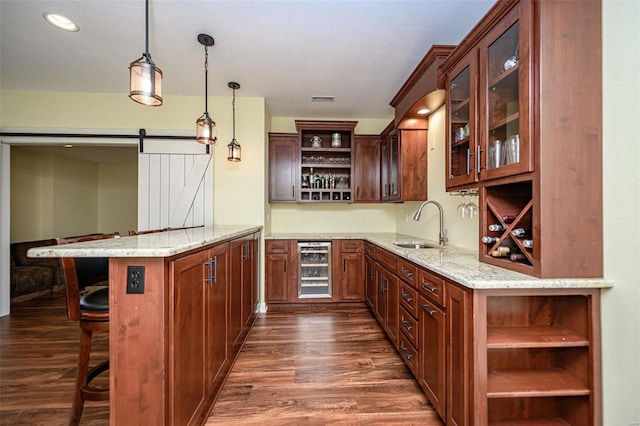 bar with decorative light fixtures, sink, wine cooler, a barn door, and dark wood-type flooring