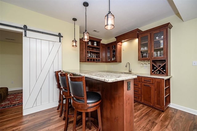 bar featuring sink, dark wood-type flooring, pendant lighting, and a barn door