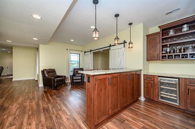 kitchen featuring a barn door, dark hardwood / wood-style floors, beverage cooler, and hanging light fixtures