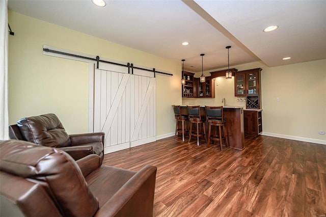 living room with a barn door, dark wood-type flooring, and sink