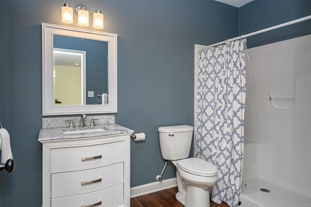 bathroom featuring toilet, hardwood / wood-style flooring, walk in shower, and vanity