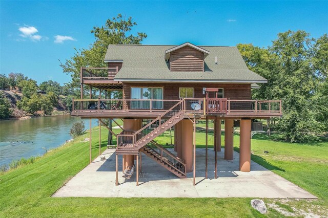 back of property with a lawn, a patio area, and a deck with water view