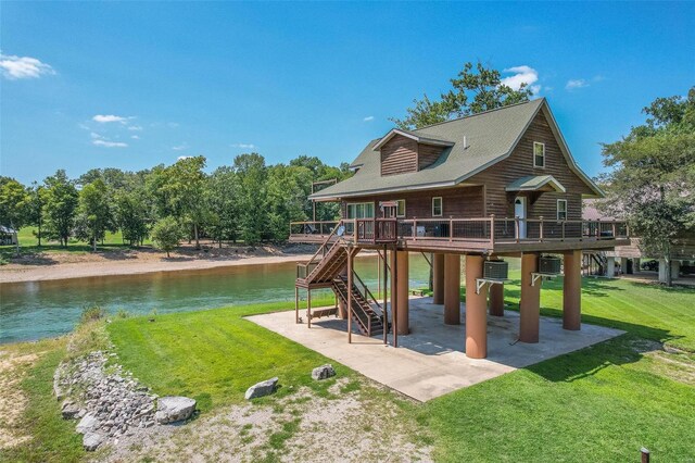 rear view of house with a patio, a deck with water view, and a yard