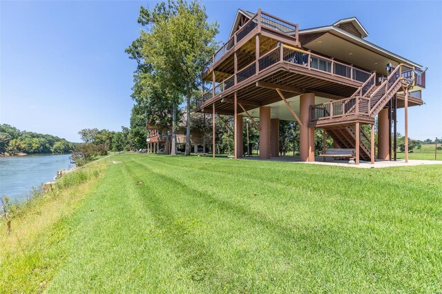 back of house with a patio area, a deck with water view, and a yard