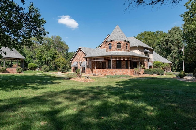 rear view of property with a lawn and a gazebo