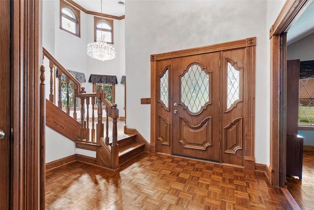 foyer with parquet flooring, plenty of natural light, a chandelier, and a high ceiling