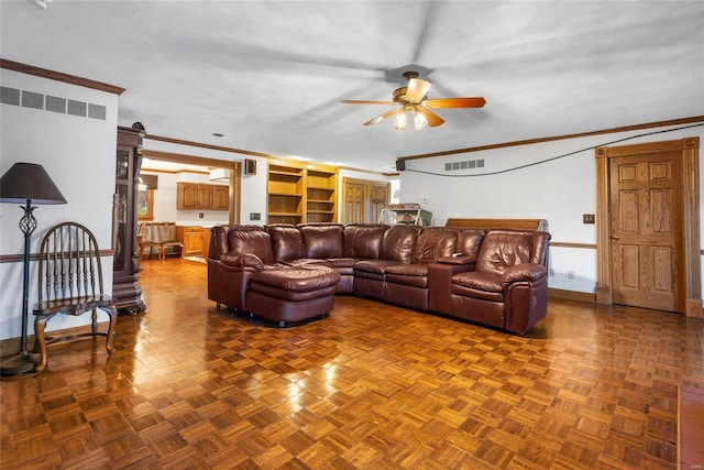 living room featuring a barn door, ceiling fan, ornamental molding, and parquet flooring