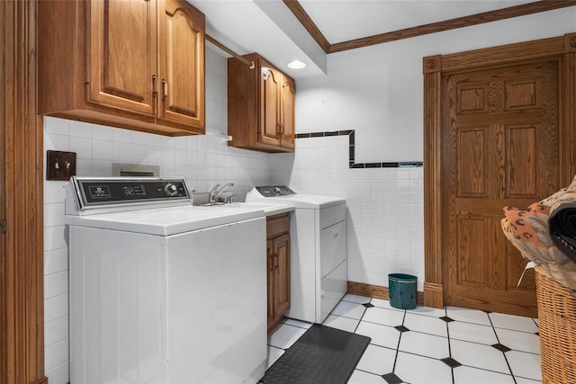 laundry room featuring ornamental molding, cabinets, separate washer and dryer, and tile walls