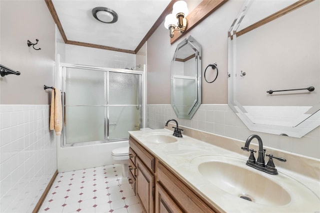 full bathroom with shower / bath combination with glass door, vanity, tile walls, toilet, and ornamental molding