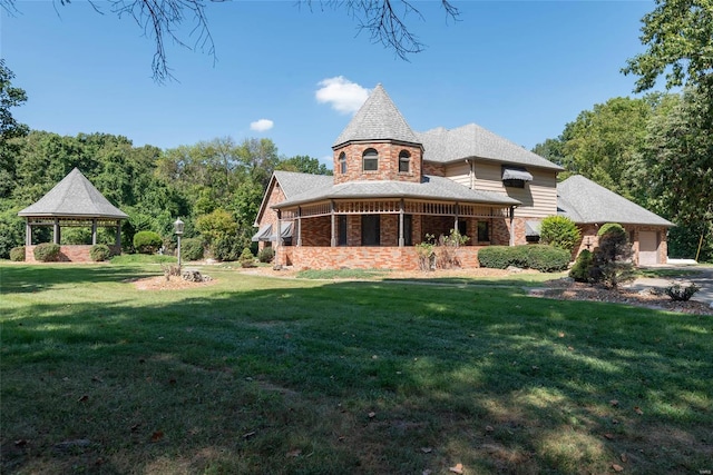 rear view of property featuring a lawn and a gazebo