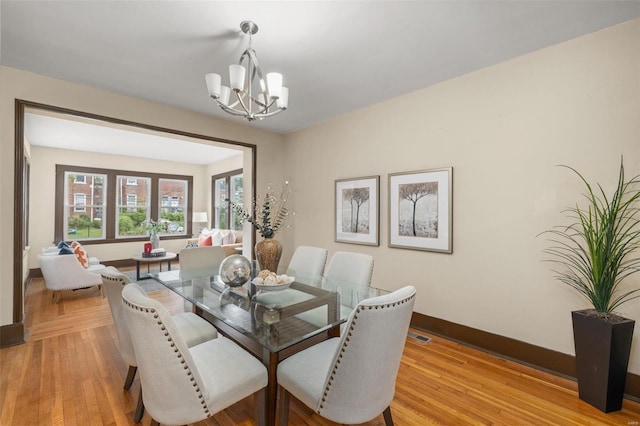 dining space with light wood-type flooring and a chandelier