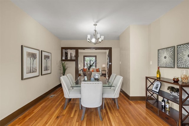 dining space with hardwood / wood-style flooring and a chandelier