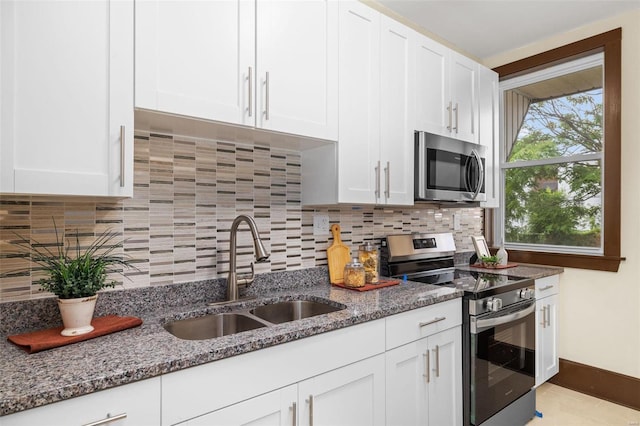 kitchen with stainless steel appliances, white cabinetry, tasteful backsplash, sink, and stone countertops