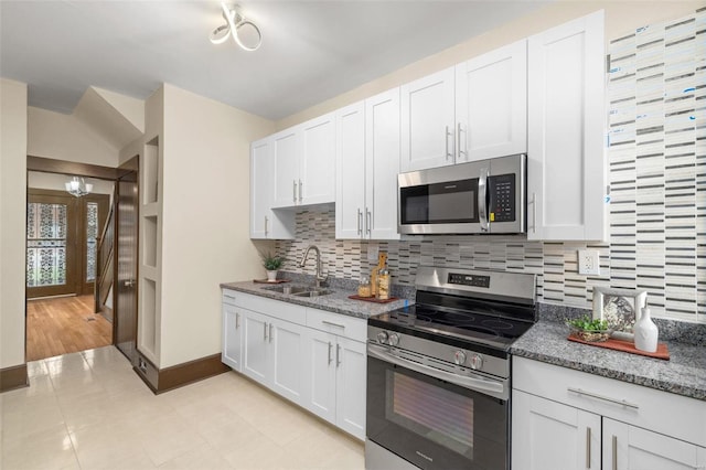 kitchen featuring dark stone countertops, light hardwood / wood-style flooring, decorative backsplash, stainless steel appliances, and white cabinets