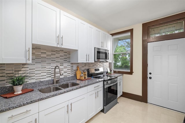 kitchen featuring appliances with stainless steel finishes, backsplash, white cabinetry, light stone countertops, and light tile patterned floors