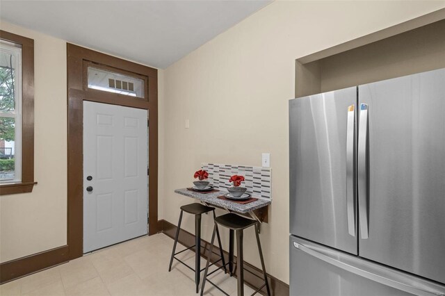 kitchen featuring light tile patterned floors, stainless steel fridge, and a kitchen breakfast bar