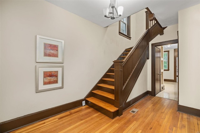 stairway featuring hardwood / wood-style floors and an inviting chandelier