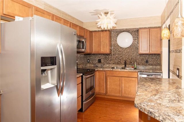 kitchen with backsplash, sink, light hardwood / wood-style flooring, and appliances with stainless steel finishes