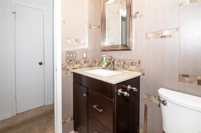 bathroom featuring vanity, toilet, and tile walls