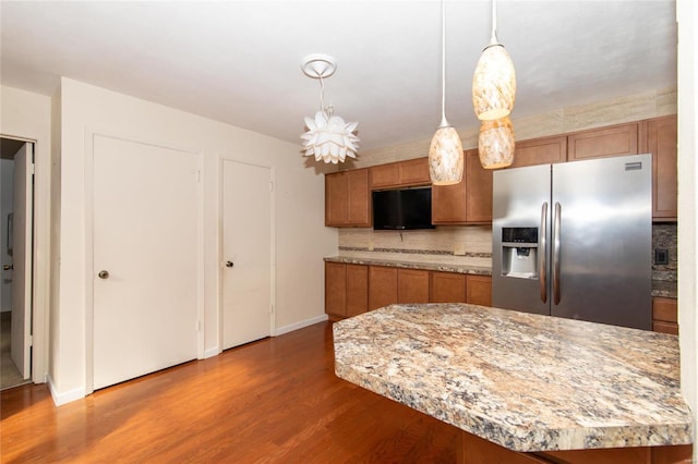 kitchen featuring a notable chandelier, stainless steel refrigerator with ice dispenser, hardwood / wood-style flooring, tasteful backsplash, and decorative light fixtures