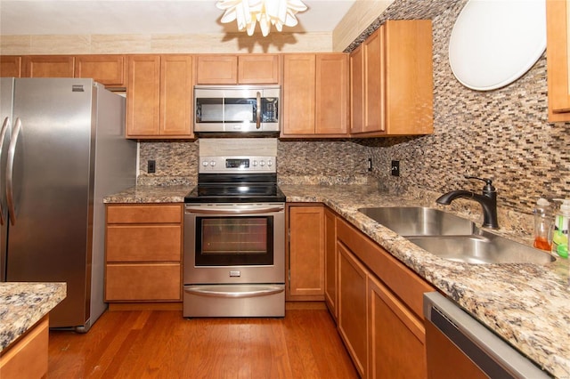 kitchen with light wood-type flooring, stainless steel appliances, backsplash, and sink