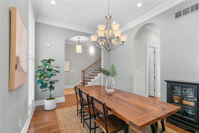 dining area featuring light wood-type flooring, a notable chandelier, and ornamental molding