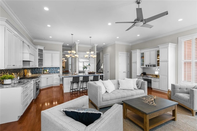 living room featuring ceiling fan with notable chandelier, ornamental molding, and wood-type flooring