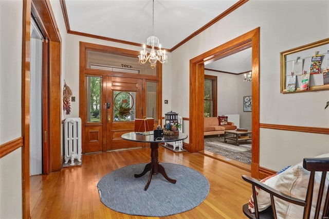 foyer entrance featuring crown molding, an inviting chandelier, radiator heating unit, and wood-type flooring