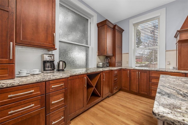 kitchen featuring light hardwood / wood-style flooring, decorative backsplash, and light stone countertops