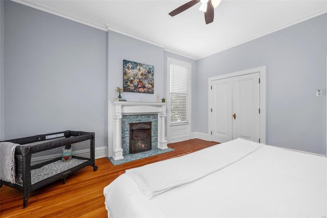 bedroom featuring a closet, ceiling fan, crown molding, and wood-type flooring