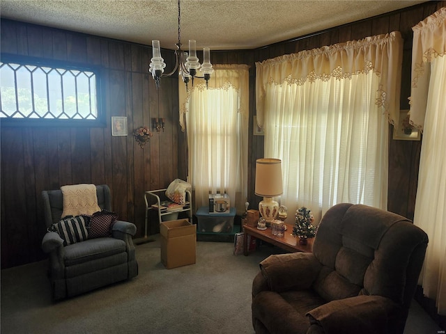 living area featuring carpet flooring, wooden walls, a chandelier, and a textured ceiling