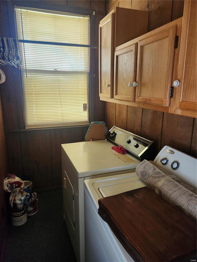 washroom with wooden walls, cabinets, and independent washer and dryer